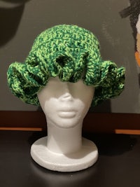 a green crocheted hat on a mannequin head