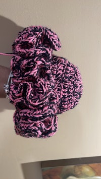 a person holding a pink and black knitted mitten