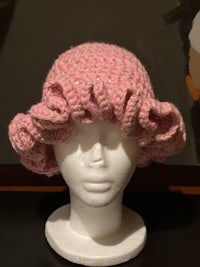 a pink crocheted hat on a mannequin head